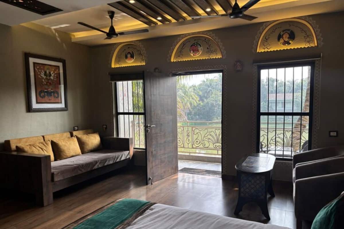 A room with a sofa, a bed, a small table, and a balcony with decorative arches.