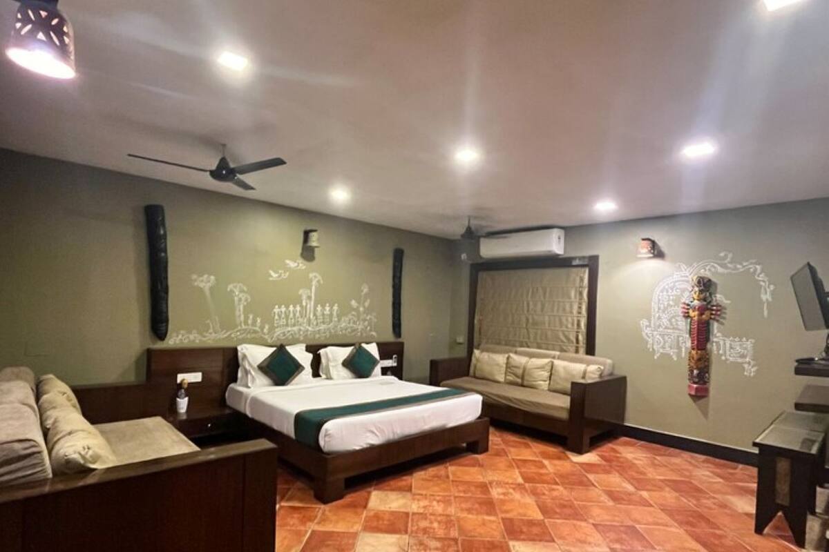 A hotel room with a bed, a sofa, a desk, and a ceiling fan.