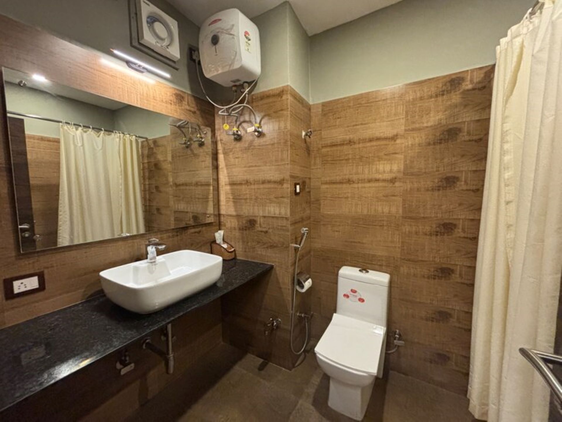 A bathroom with a sink, mirror, shower, and toilet.