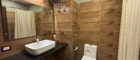 A bathroom with a sink, mirror, shower, and toilet.