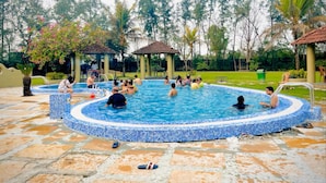 A swimming pool with tiled edges, surrounded by a stone deck, and shaded by a gazebo. - Breathing Earth (Diamond Harbour)