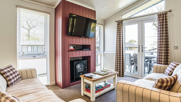 Een woonkamer met een open haard, een aan de muur bevestigde televisie en een bank.
