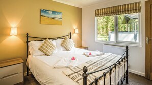 Een slaapkamer met een bed, nachtlampjes, een schilderij, een raam met uitzicht en een radiator.