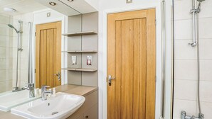 Een badkamer met een wastafel, spiegel, houten deuren en een douche.
