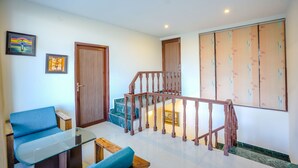 A spacious living area with a wooden staircase, a blue sofa, and a glass coffee table. - Kia Kasauli - 3 BHK, Villa with Kitchen+BonFire+Cook (Kasauli)