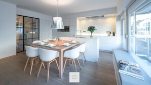 A modern kitchen with a dining area, a large window, and a view of the city. - Comfort Floor, light and spacious at a top location (Knokke-Heist)