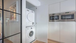 A compact laundry area with a front-loading washer and dryer, and a built-in oven. - Comfort Floor, light and spacious at a top location (Knokke-Heist)
