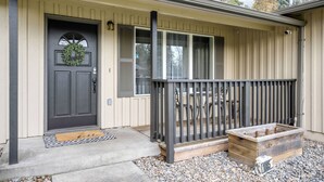 A house with a dark front door, a porch with a railing, and a small wooden planter. - Splendid Location, Single Level, Pet Friendly, Huge Fenced Yard, BBQ, Games, Next to School Fields (Hillsboro)