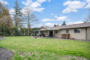 Einbungalow mit überdachter Terrasse und Rasen.