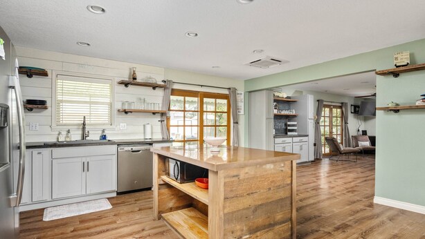 A spacious kitchen with wooden flooring, white cabinets, and a central island. - Splendid Location, Single Level, Pet Friendly, Huge Fenced Yard, BBQ, Games, Next to School Fields (Hillsboro)