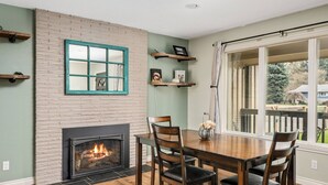 A dining area with a brick fireplace, wooden chairs, and a table. - Splendid Location, Single Level, Pet Friendly, Huge Fenced Yard, BBQ, Games, Next to School Fields (Hillsboro)