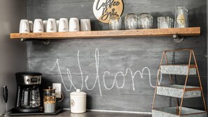 A coffee station with a coffee maker, mugs, and a welcome sign on a chalkboard wall. - Splendid Location, Single Level, Pet Friendly, Huge Fenced Yard, BBQ, Games, Next to School Fields (Hillsboro)