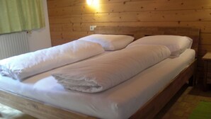 A wooden bed with white linens and pillows, a bedside table, and a wall-mounted light. - Wonderful apartment with fantastic view Top 2 (2nd floor) (Wald am Arlberg)
