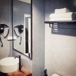 A bathroom with a large mirror, a sink, and a towel rack. - into the town (Krabi)