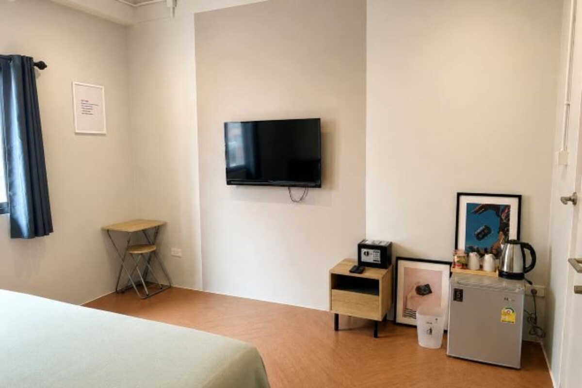 A hotel room with a bed, a television, a small table, a refrigerator, and a coffee maker.