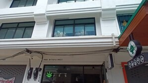 Un edificio con fachada que muestra el rótulo "PROD BITTER & SWEET" y un anuncio para "DJ Cannabis".