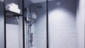 Un baño moderno con ducha de vidrio, inodoro blanco y tocador de madera con lavamanos.