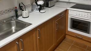 Una cocina con armarios de madera, un lavamanos de acero inoxidable, un tostador y un horno.