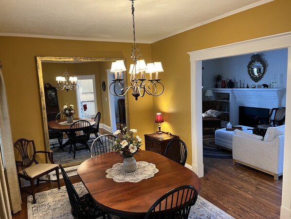 A dining area with a wooden table, chairs, and a chandelier. There is a mirror on the wall and a fireplace in the background. - Historic home in the Village of Lewiston - short walk to dining, concerts, river (Lewiston)