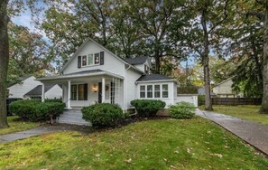 Une maison à deux étages avec un porche à l’avant, un hall d’entrée abrité et un petit jardin devant, agrémenté d’un chemin.