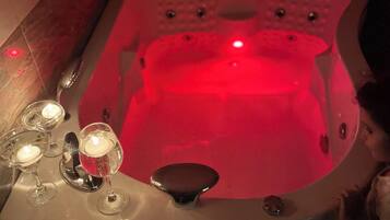 A hot tub with a red light, surrounded by candles and glasses.