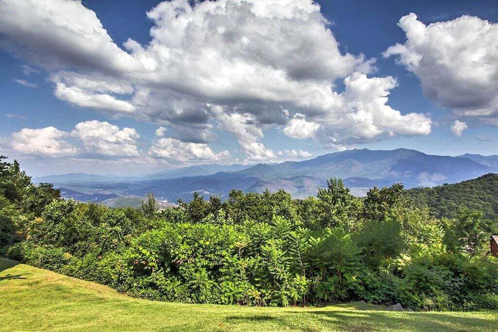 Üppige grüne Landschaft mit Blick auf ferne Berge unter teils bewölktem Himmel.
