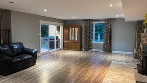 A spacious living room with a wooden cabinet, a black leather couch, and a sliding glass door leading to a patio. - Parkhill / GrandBend - Spanish Style Private Acerage property (Parkhill)
