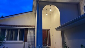 A house with a central arched entryway, a visible door, and a small porch area with plants. - Parkhill / GrandBend - Spanish Style Private Acerage property (Parkhill)
