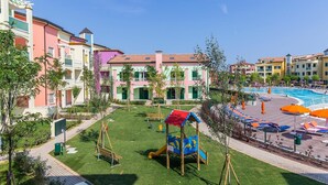 A residential building with colorful facades, a playground, and a swimming pool.