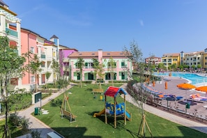 A residential building with colorful facades, a playground, and a swimming pool.