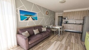 A modern living room with a sofa, dining table, and kitchen area.