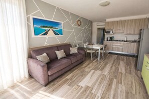 A modern living room with a sofa, dining table, and kitchen area.