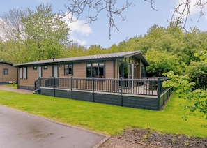 A single-story building with a porch, a fenced deck, and a clear view of the surrounding greenery.