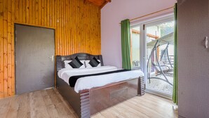 A wooden-paneled room with a bed, a sliding glass door to an outdoor area, and a door to another room.