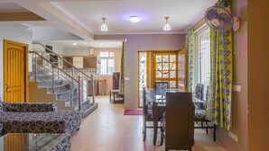 A spacious living area with a staircase, dining table, and chairs.