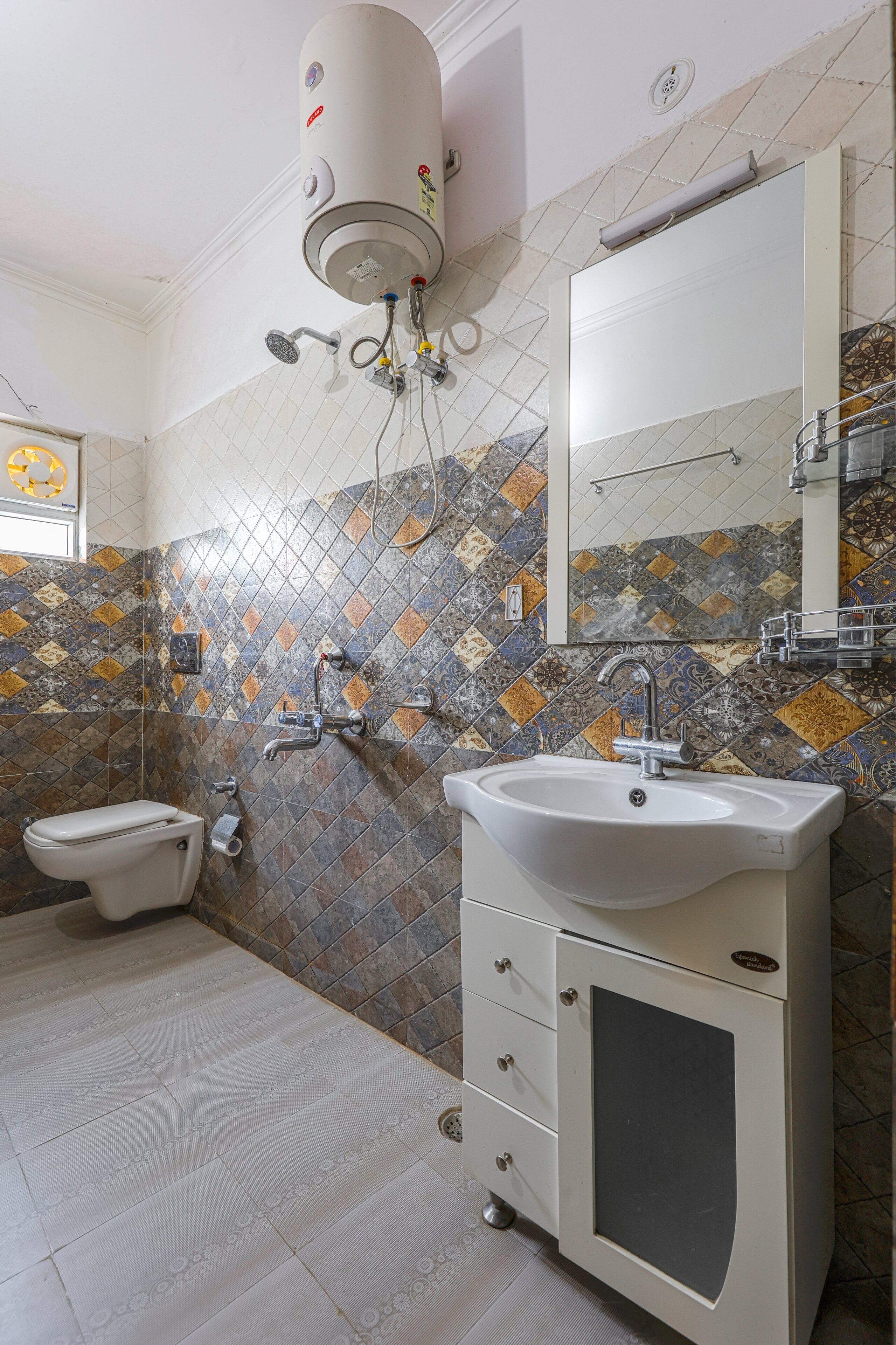 Et badeværelse med toilet, håndvask og bruser.