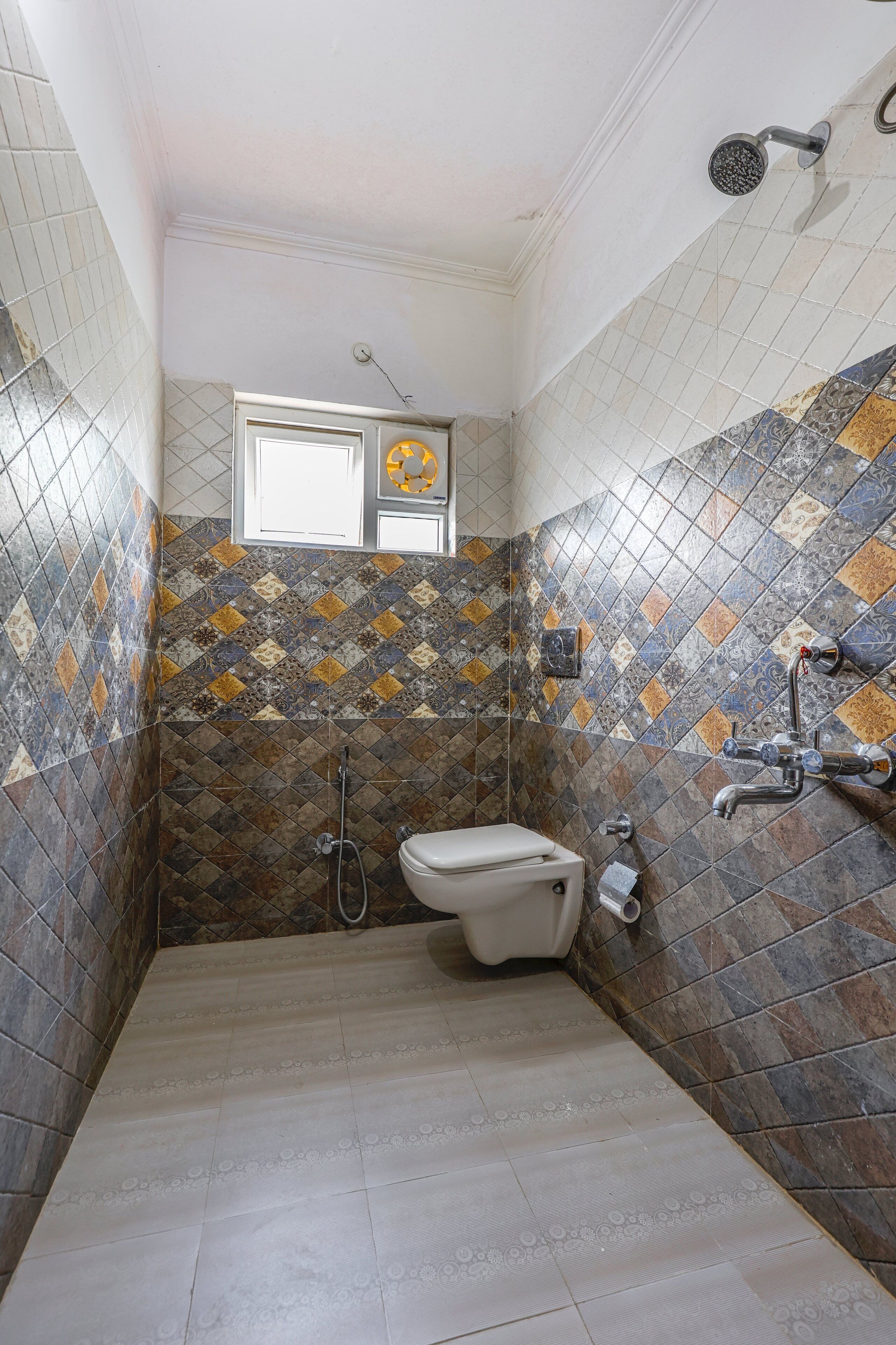 Une salle de bain avec des toilettes, une douche et une fenêtre.