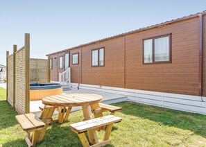 Une maison mobile en bois dotée d’un bain à remous, d’une terrasse et d’une table de pique-nique.