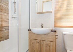 Une salle de bain avec un lavabo blanc, un meuble-lavabo en bois, un miroir et des toilettes.