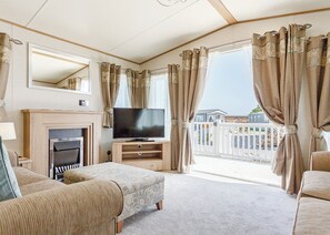 Un salon avec une cheminée, un téléviseur et un balcon donnant sur une maison.