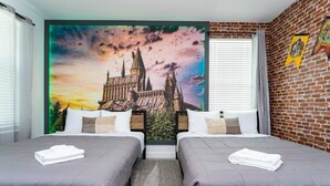 Een hotelkamer met twee bedden, een groot wandtapijt met een kasteel en een bakstenen muur met een familiewapen.