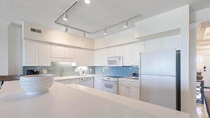 Een moderne keuken met witte kasten, een roestvrijstalen koelkast, een magnetron en een vaatwasser.