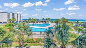 Een hotel met een zwembad, palmbomen en uitzicht op zee.
