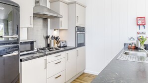 Et moderne køkken med rustfrie apparater, hvide skabe og en indbygget ovn.