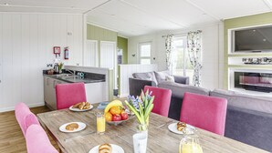 En moderne stue med spiseplads, et køkken og et fjernsyn.