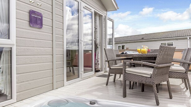 Et område med jacuzzi, fletstole, et bord og et skilt på væggen.