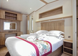 A bedroom with a bed, a TV, wooden shelving, and a mirror. - Wadebridge Premier 2 (Newquay)