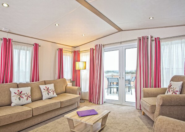 A hotel room with a sofa, armchair, and a table with a book.
