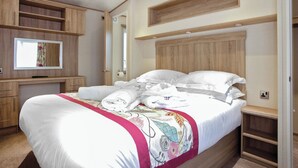 Ein Schlafzimmer mit einem Bett, einem Fernseher, Holzregalen und einem Spiegel.