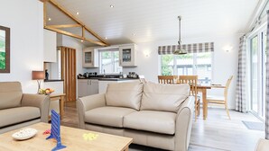 A modern living room with a sofa, coffee table, and a dining area with a table and chairs. - 1 bedroom accommodation in Newton Saint Loe, Nr Bath (Newton Saint Loe, Nr Bath)